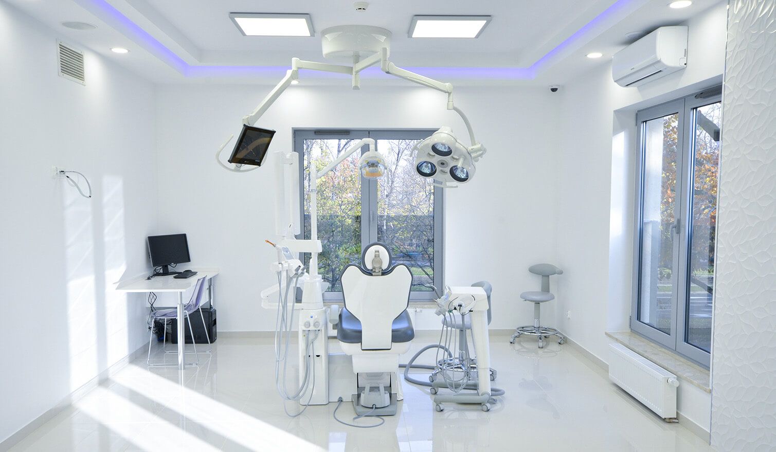 Interiér zubní ordinace s křeslem, počítačem a lampou, který zdůrazňuje význam správného osvětlení ve stomatologii | Lumedic