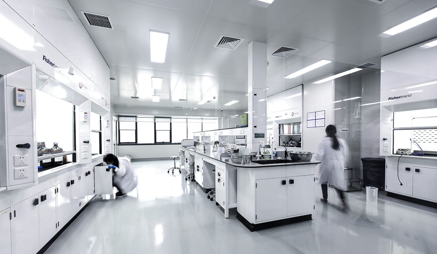 Farmaceutická laboratoř s bílými stěnami a skříňkami, osvětlená jasným světlem